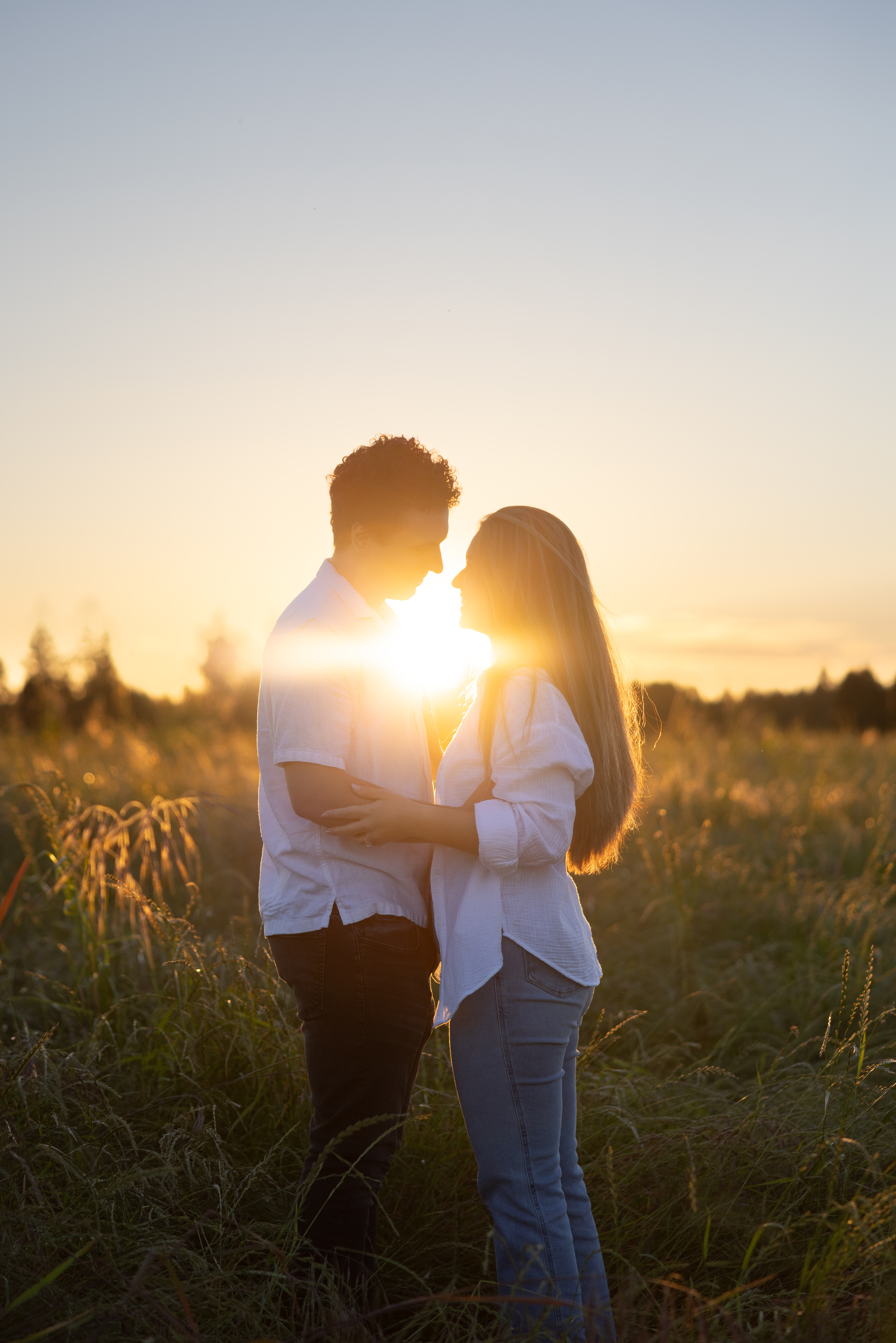 Couple silhouetted against a blazing golden-hour sky in an open field